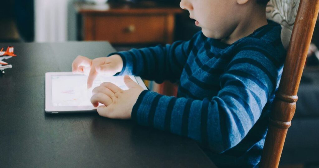 child using tablet at kitchen table