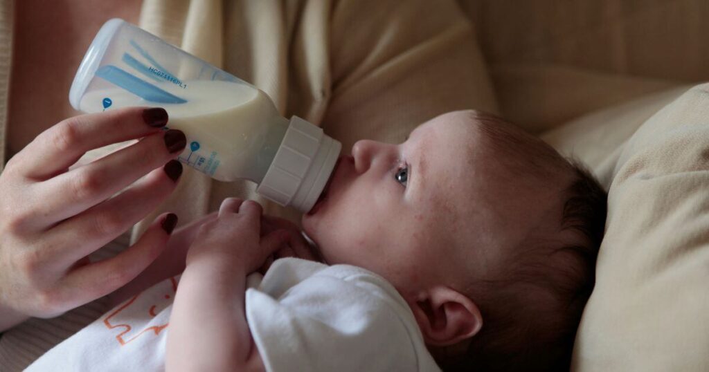 adult feeding a baby with a baby bottle